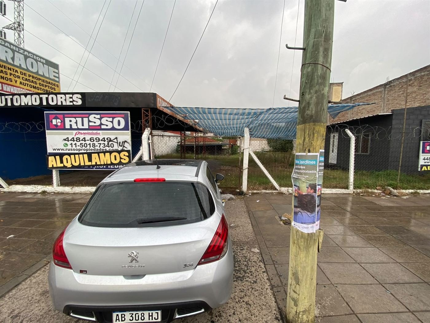 Un auto estacionado frente a un predio con cartel de alquilamos
