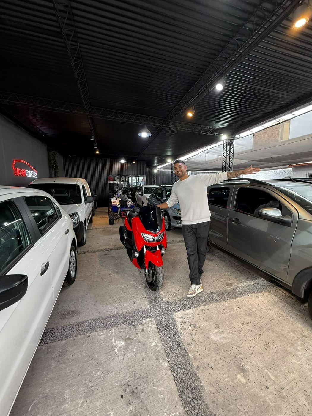 Interior de la agencia con autos y una moto roja