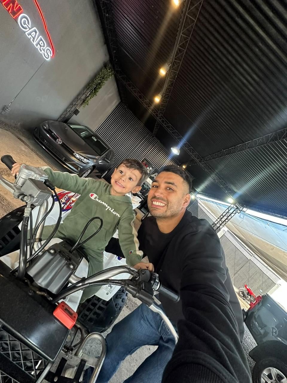 Nacho sonriendo con su hijo sobre un cuatriciclo en la agencia
