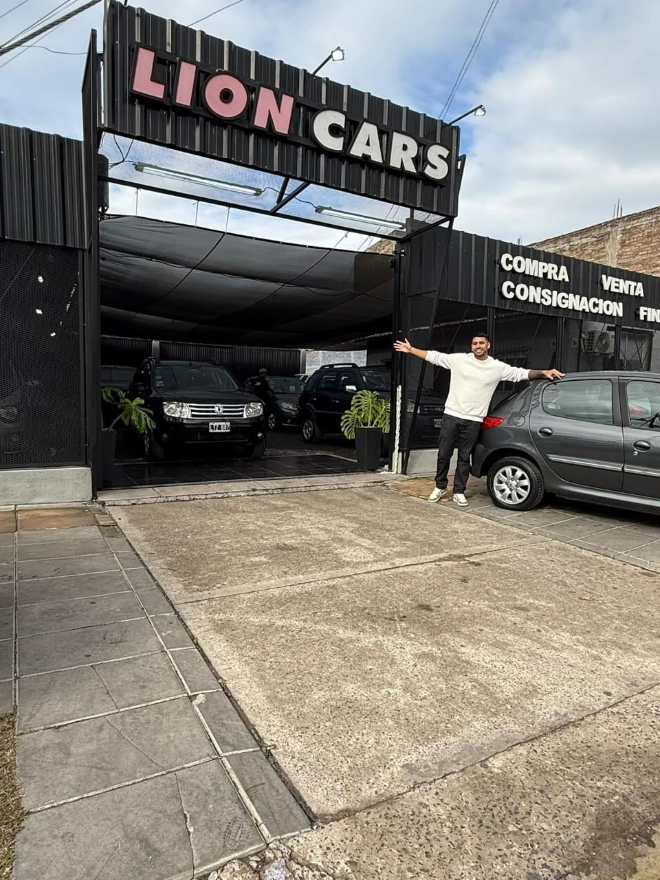Nacho con los brazos abiertos frente a la agencia Lion Cars terminada