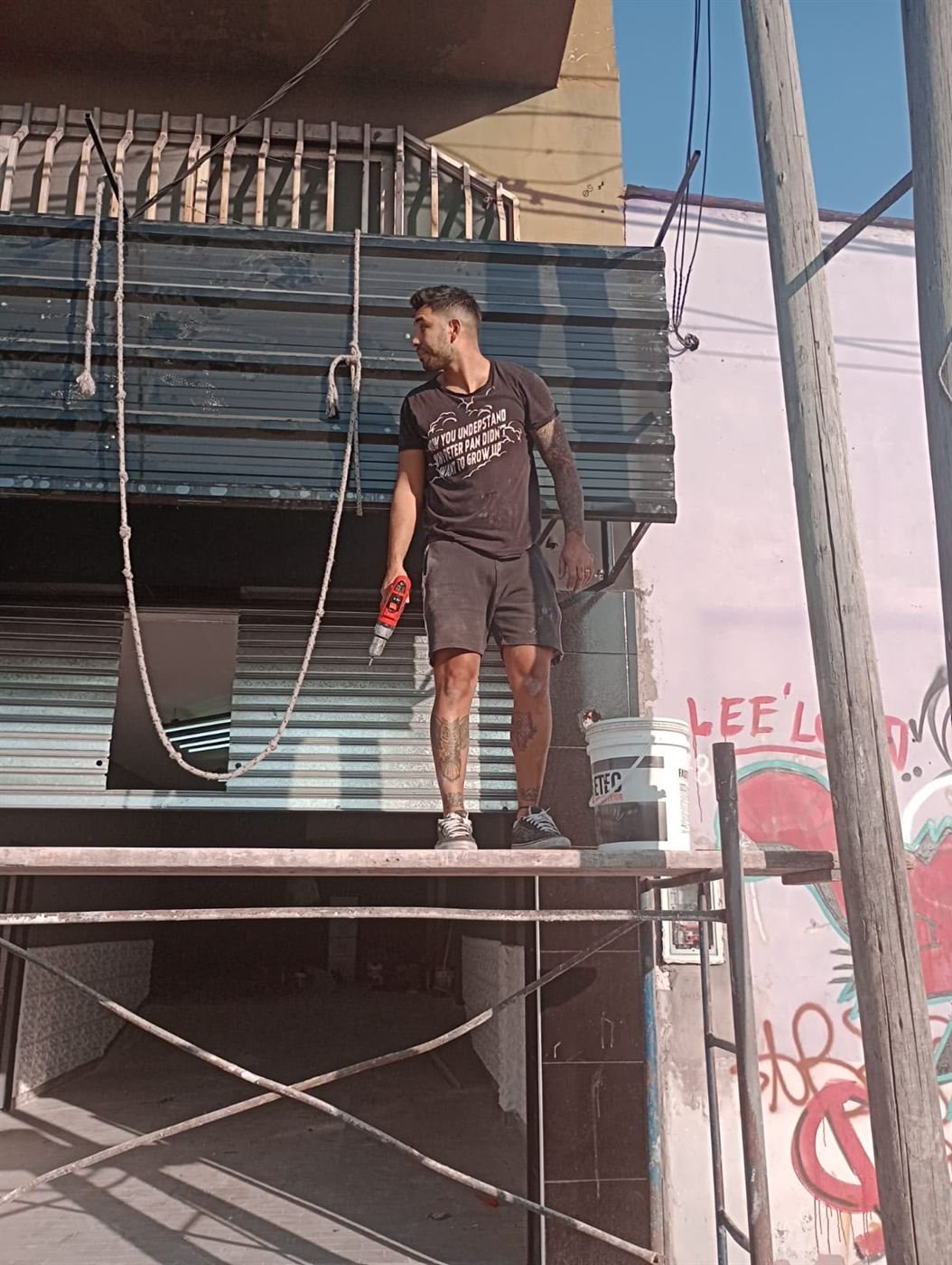 Nacho sobre una escalera pintando la persiana de la primera agencia
